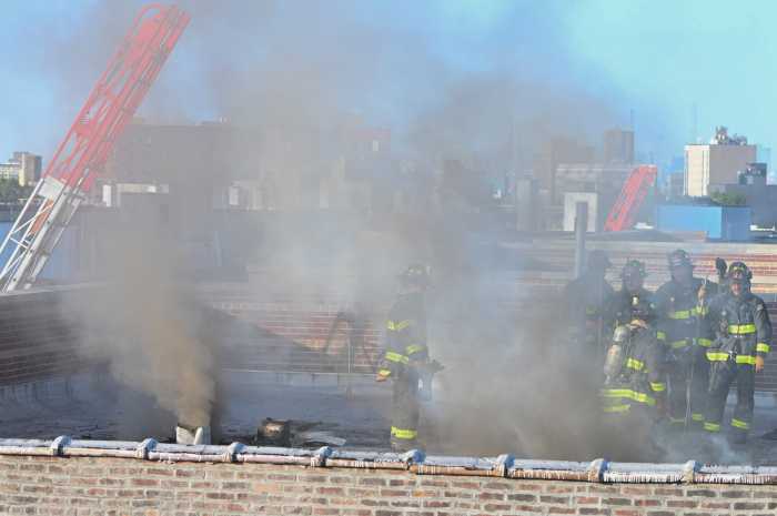 Firefighters work to perform a trench cut to stop fire from extending into the B wing during a four alarm fire at 3422 Dekalb Avenue on Thursday, August 20.