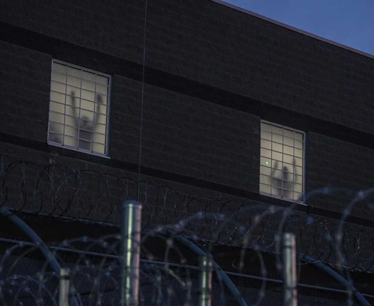 As night fell, the shadows of detainees could be seen past the barbed wire fences and inside the building through the windows as they flicked the lights and appeared to jump up and down as they attempted to communicate with those outside on the outside, much to the delight of protesters who yelled to them through megaphones.