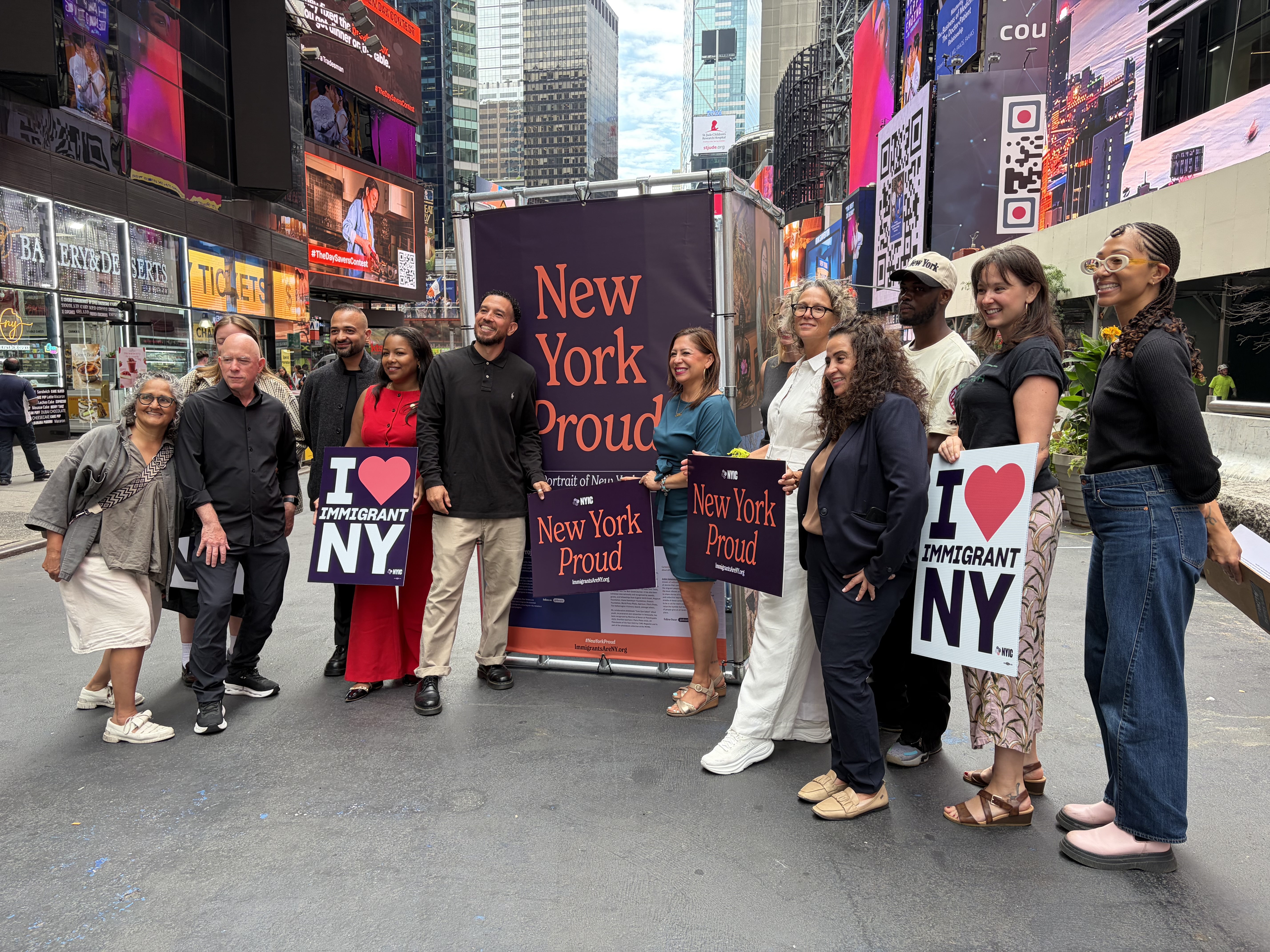 Photographer Oscar B. Castillo, Assembly member Amanda Septimo, State Senator Jessica González-Rojas, and members of New York Immigration Coalition pose at the launch of the third annual New York Proud art installation in Time Square.